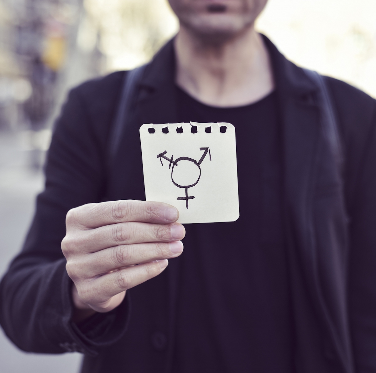 Person hält ein Zettel, darauf das Transgender-Icon